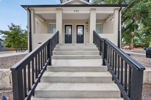 A building with a double door entrance, a set of concrete steps, and a black metal railing.