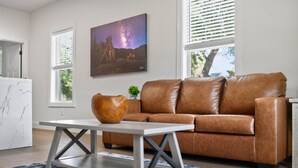 A modern living room with a brown leather sofa, a white coffee table, and a painting of a starry night sky.