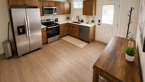 Una cucina moderna con elettrodomestici in acciaio inossidabile, mobili in legno, una lavastoviglie e un tavolo da pranzo in legno.