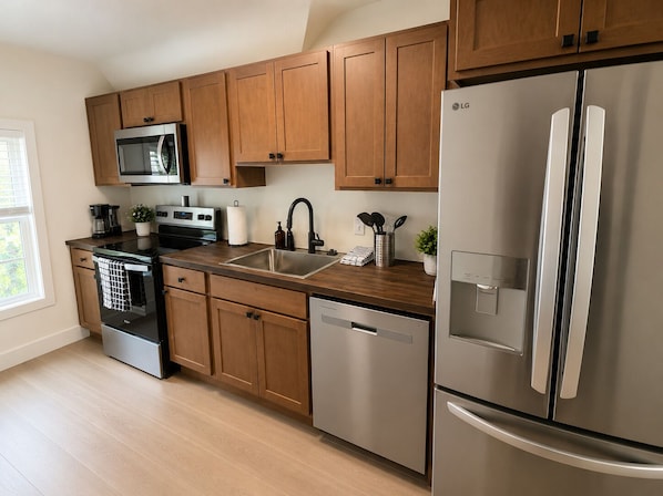 A modern kitchen with stainless steel appliances, wooden cabinets, and a dishwasher.