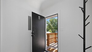 Puerta que da a un balcón con barandilla de madera y un felpudo.