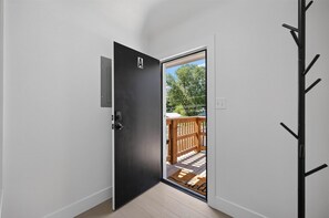 A door leading to a balcony with a wooden railing and a welcome mat.