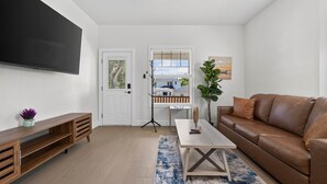 A modern living room with a brown leather sofa, a wooden coffee table, and a flat-screen TV mounted on the wall.