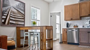 A modern kitchen with wooden cabinets, a stainless steel dishwasher, and a bar area with stools.