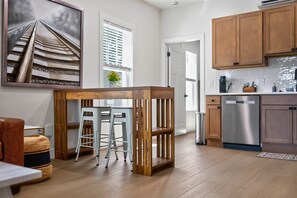 A modern kitchen with wooden cabinets, a stainless steel dishwasher, and a bar area with stools.
