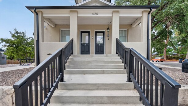 A building with a double door entrance, a set of concrete steps, and a black metal railing.