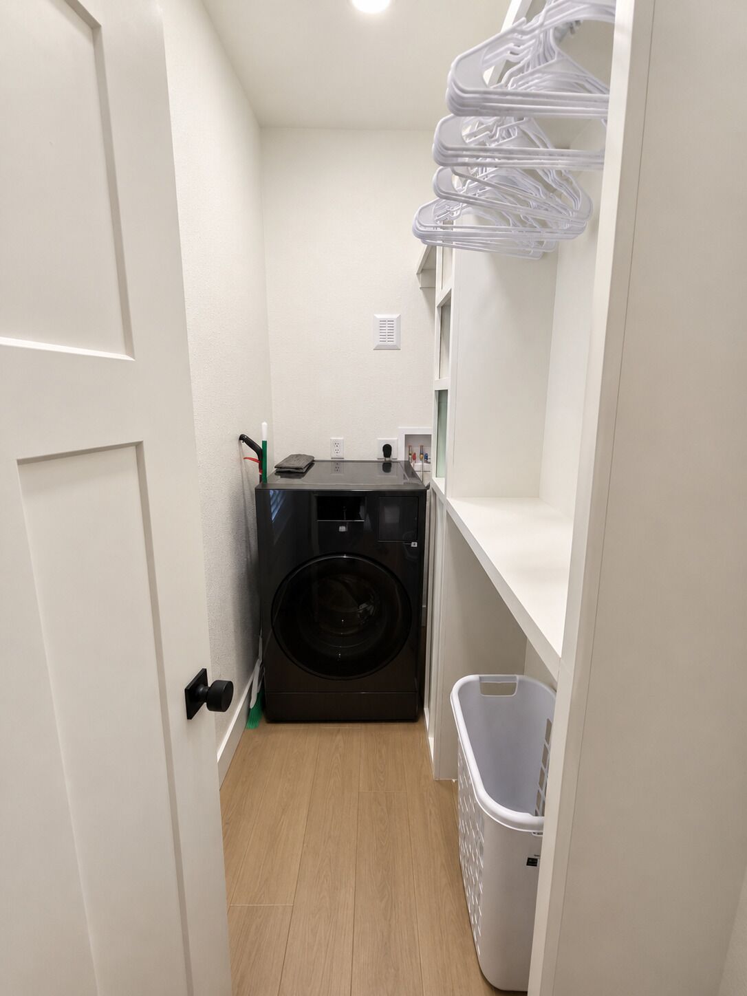 Een wasserette met een wasmachine, een droogrek en een prullenbak.