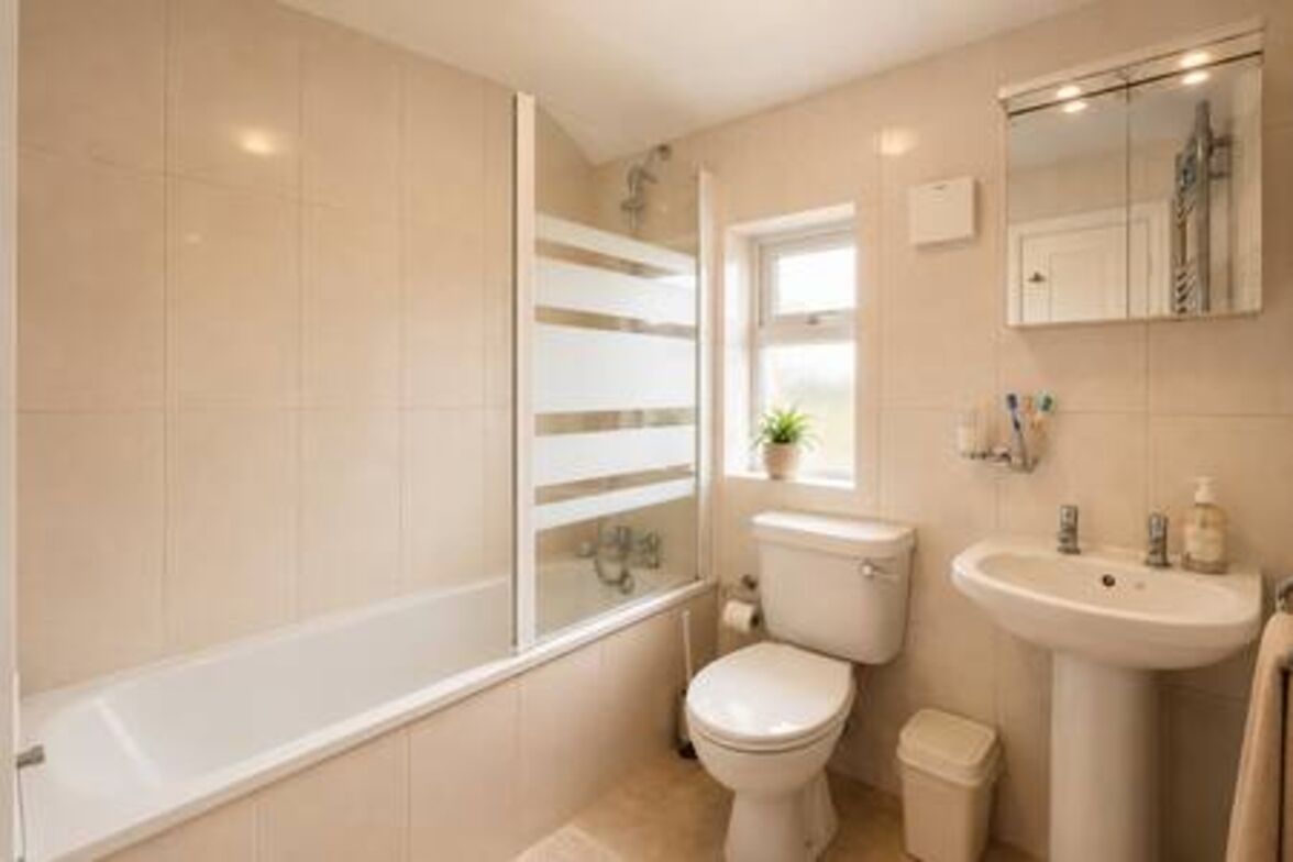 A bathroom with a bathtub, toilet, sink, and a window.
