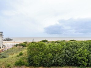 Eine Küstenlandschaft mit Strand, einem Steg und einem Gebäude mit flachem Dach.