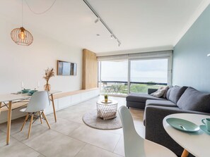 Una sala de estar moderna con comedor, ventanas amplias y vistas al exterior.
