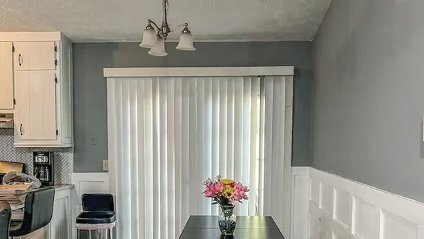 A dining area with a table and benches, a kitchen in the background, and a window with blinds. - Sweet Spot - Bedroom 2 with shared Bathroom (Stone Mountain)
