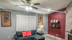 A living room with a sectional sofa, a ceiling fan, a fireplace, and framed artwork on the walls. - Sweet Spot - Bedroom 2 with shared Bathroom (Stone Mountain)