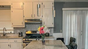 A kitchen with a central island, bar stools, a toaster, and a vase with flowers. - Sweet Spot - Bedroom 2 with shared Bathroom (Stone Mountain)