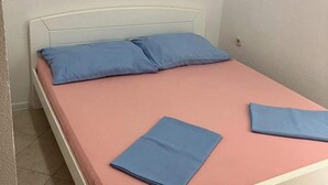 Ein Bett mit einer rosa Matratze und zwei blauen Kissen.