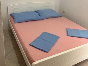 Ein Bett mit einer rosa Matratze und zwei blauen Kissen.
