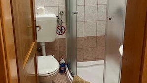 Ein Badezimmer mit Toilette, Dusche und einem Handtuch auf dem Boden.