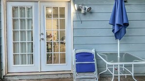 Ett hus med en vit dörr, ett blått parasoll och ett vitt bord med en blå stol.