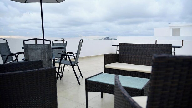 A rooftop terrace with wicker furniture, a table, and an umbrella. - Private Rooftop Terrace · BBQ · City Views · 2BR Mazatlán (Mazatlán)