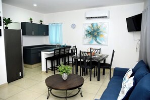 Un espacio habitable compacto con kitchenette, comedor y sofá.