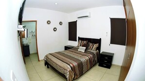 A bedroom with a bed, bedside tables, a wardrobe, an air conditioning unit, and a bathroom with a sink and mirror. - Private Rooftop Terrace · BBQ · City Views · 2BR Mazatlán (Mazatlán)