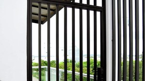 A closed black metal gate with a view of a green landscape and a building in the background. - Private Rooftop Terrace · BBQ · City Views · 2BR Mazatlán (Mazatlán)