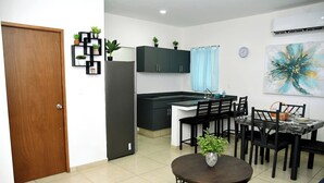 A modern kitchen with dark cabinets, a stainless steel refrigerator, and a dining area with a round table and chairs. - Private Rooftop Terrace · BBQ · City Views · 2BR Mazatlán (Mazatlán)
