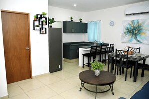 Una cocina moderna con armarios oscuros, un refrigerador de acero inoxidable y un comedor con una mesa redonda y sillas.
