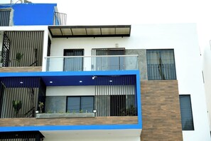Un edificio moderno de varios pisos con balcones, ventanas amplias y una combinación de materiales de madera y concreto.