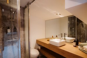 Une salle de bain moderne avec une douche à parois de verre, un meuble-lavabo en bois doté de deux vasques et un grand miroir.