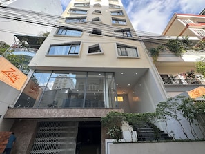A multi-story building with a modern design, featuring balconies, large windows, and a visible entrance.