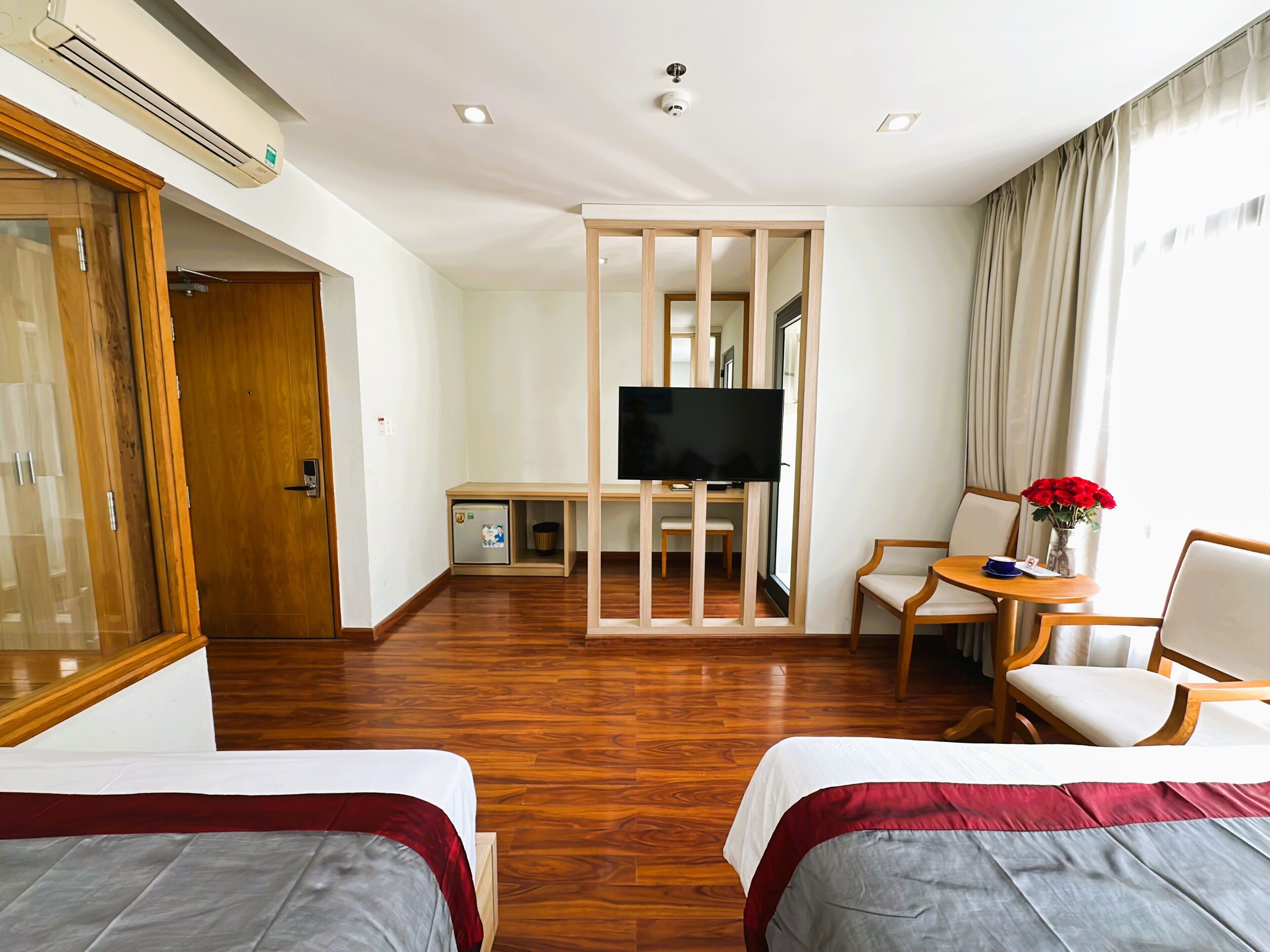 A hotel room with two beds, a TV, a desk, and a chair.