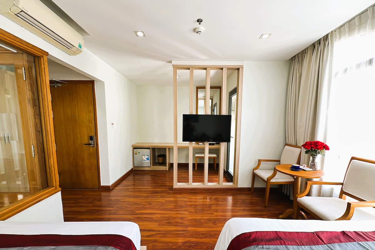 A hotel room with two beds, a TV, a desk, and a chair.