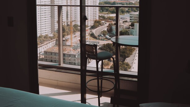 Une pièce avec une grande fenêtre, un lit, une chaise et une table.