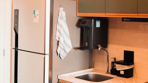 Une cuisine compacte équipée d’un réfrigérateur, d  ’une machine à café et d’un évier.