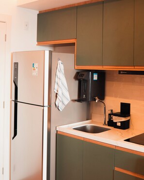 A compact kitchen with a refrigerator, coffee machine, and a sink. - Green Loft - Wonderful City (Rio de Janeiro)