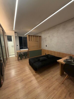 A modern apartment with a wooden floor, a black sofa, a dining table, and a kitchen area. - Green Loft - Wonderful City (Rio de Janeiro)