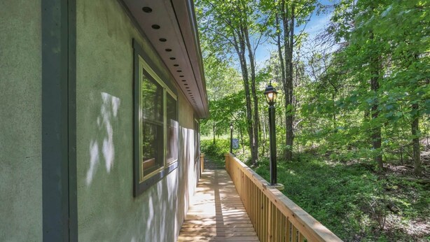 A wooden deck with a railing, surrounded by trees. - Honey Ridge Forest Retreat (Benton Township)