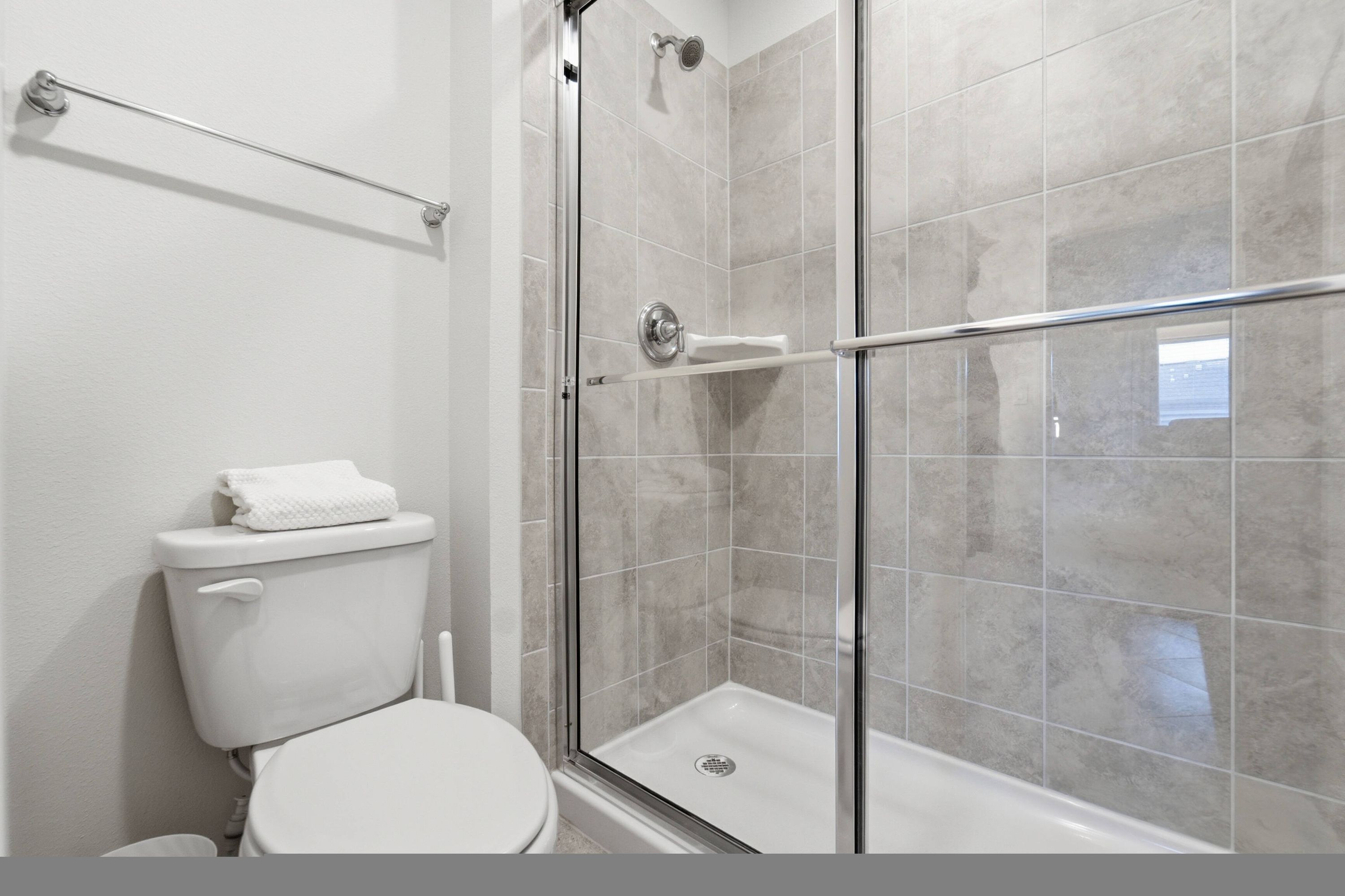 Une salle de bain comprenant des toilettes, une douche avec une porte en verre et un porte-serviettes.