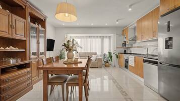 Een moderne keuken met een eethoek, houten kastjes, een roestvrijstalen koelkast en een eettafel met stoelen.