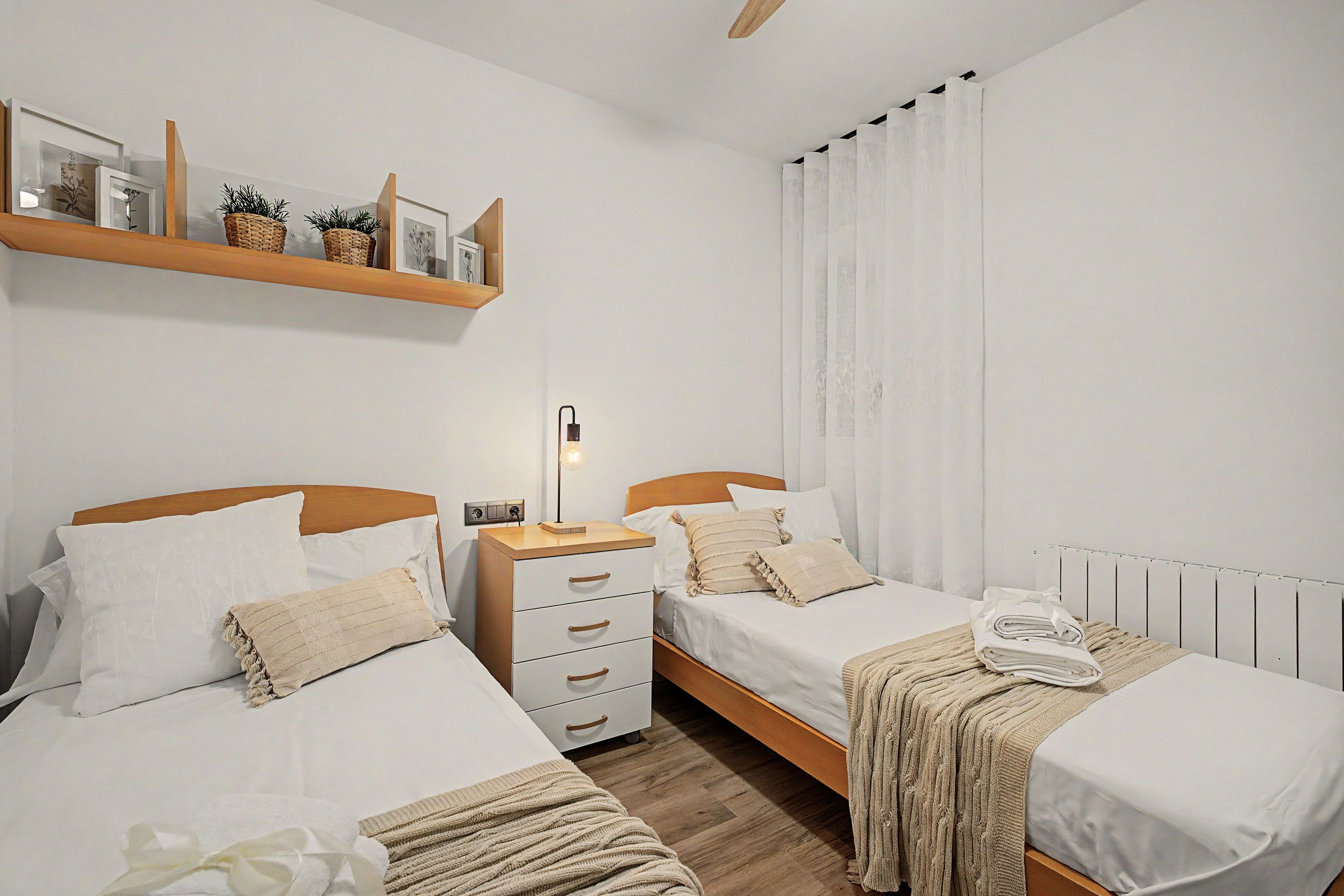 Et hotelværelse med to senge, et natbord, en lampe og en radiator.