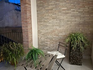 Eine Terrasse mit einer Holzbank, einem Blumentopf und einer Backsteinmauer.
