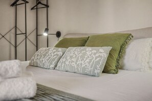 A bed with white bedding, two pillows with floral patterns, and a green throw blanket. - Apartment 'Rural Ca La Roser' with Private Terrace, Wi-Fi and Air Conditioning (L'Espluga de Francolí)