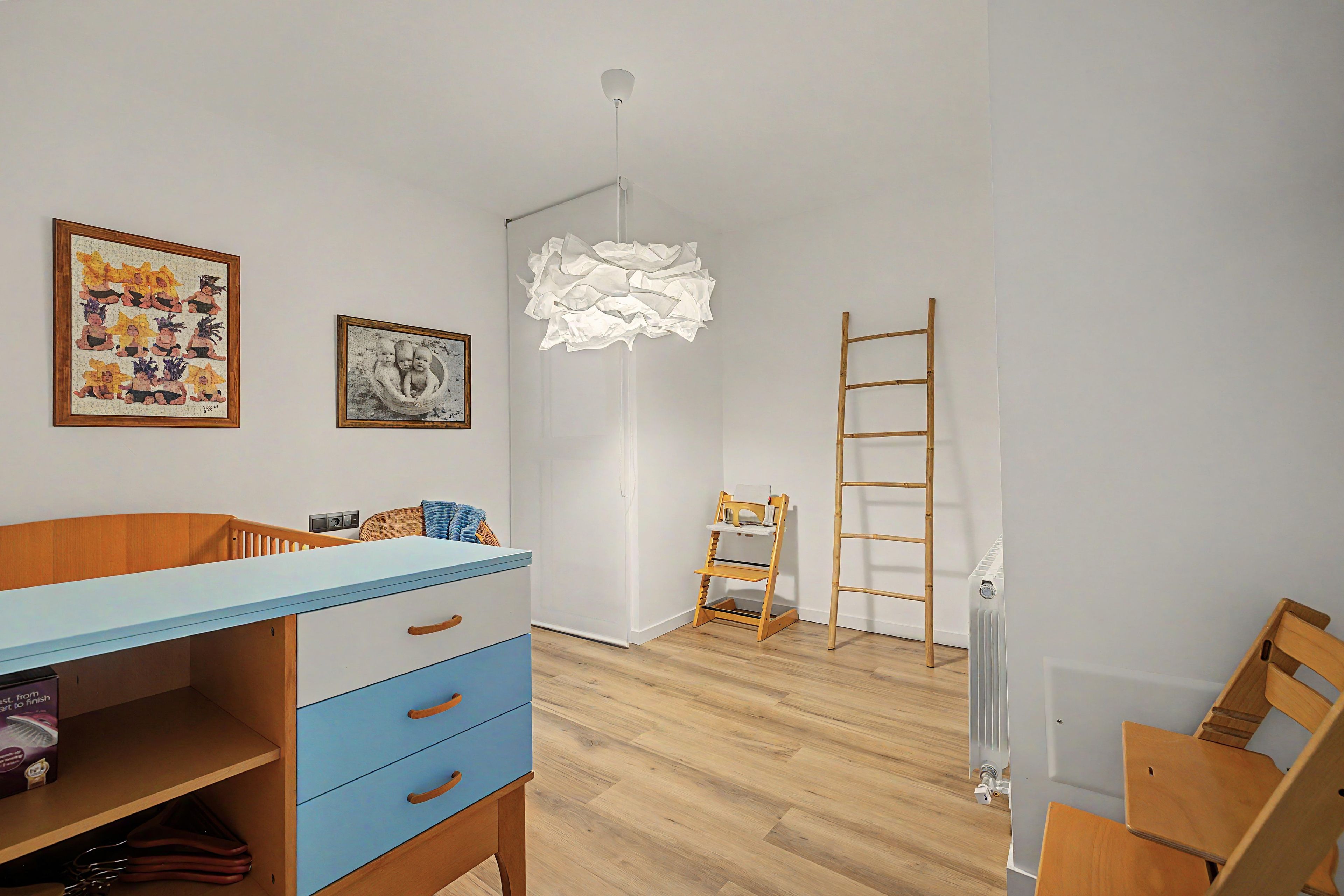 A child's room with a wooden desk, a chair, a ladder, and a radiator.