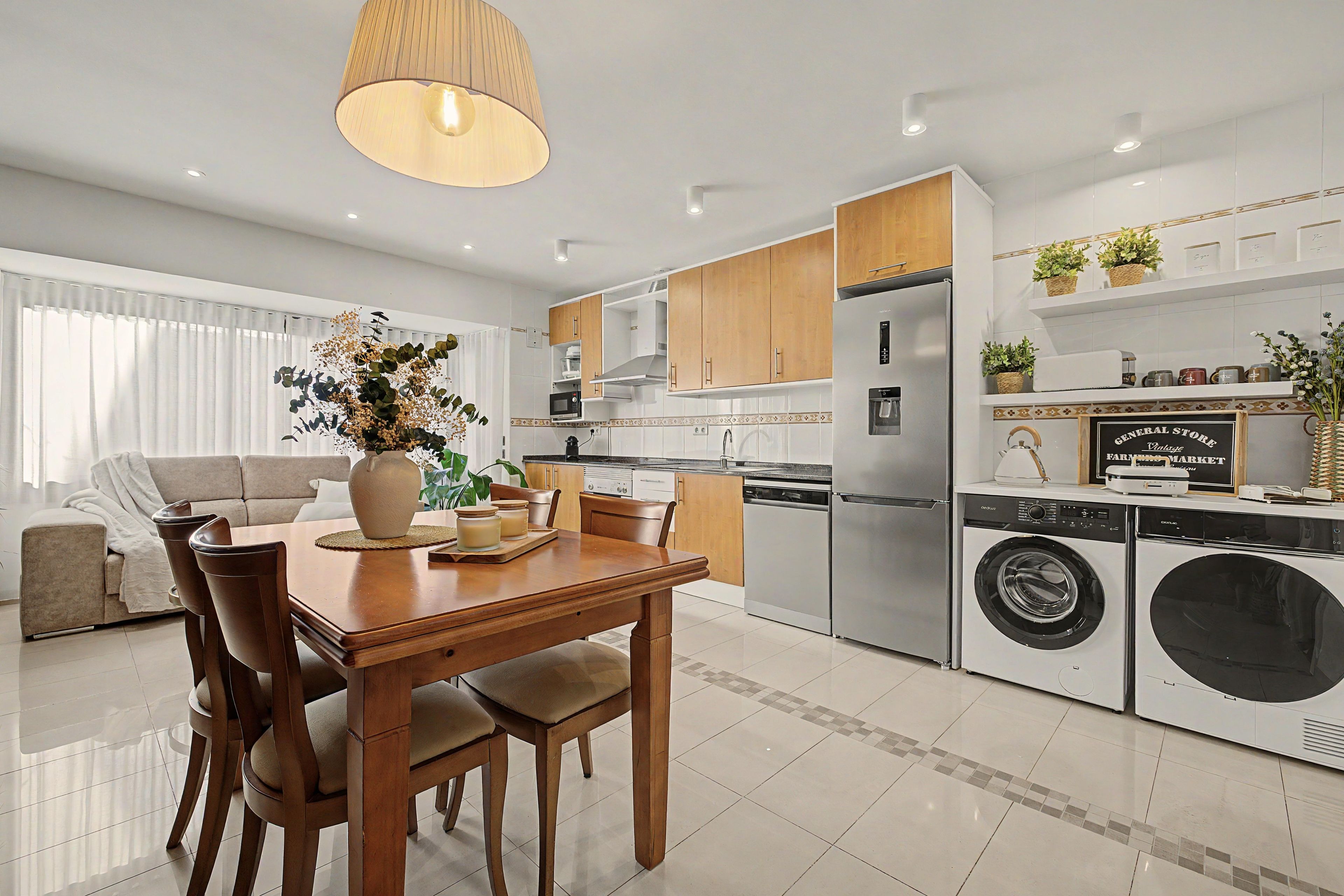 A modern kitchen with a dining area, stainless steel appliances, and a built-in washer and dryer.