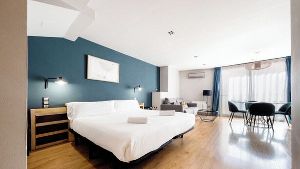 Ein modernes Hotelzimmer mit einem großen Bett, einem Schreibtisch und einer Essecke mit Stühlen.