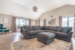 Ein geräumiges Wohnzimmer mit einem Ecksofa, einem Türkis-Armlehnstuhl und einem großen Fenster.