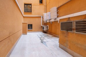 Ein schmaler Korridor mit Fliesenboden, einem kleinen Fenster und einer Klimaanlage.