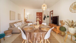 Ein Wohnzimmer mit rundem Tisch, einer Couch, einem Fernseher und Dekorationselementen.