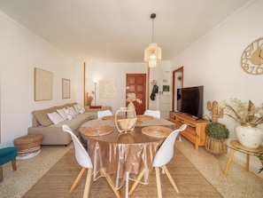 Ein Wohnzimmer mit rundem Tisch, einer Couch, einem Fernseher und Dekorationselementen.