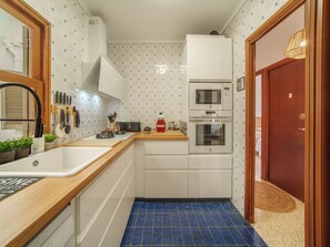 Eine kleine Küche mit Spüle, Arbeitsplatte und zwei Backöfen.
